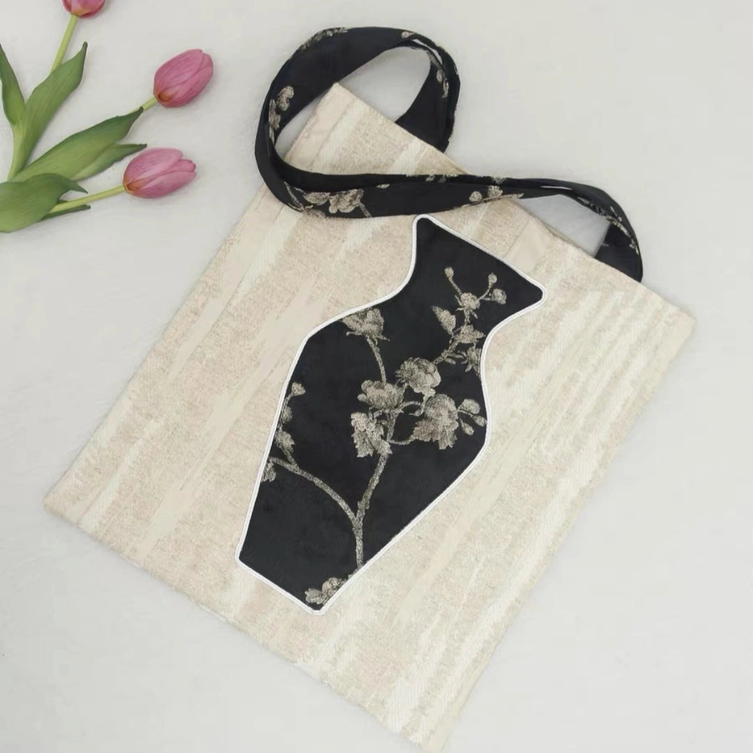 Close-up of the embroidered vase pocket on the black tote bag 