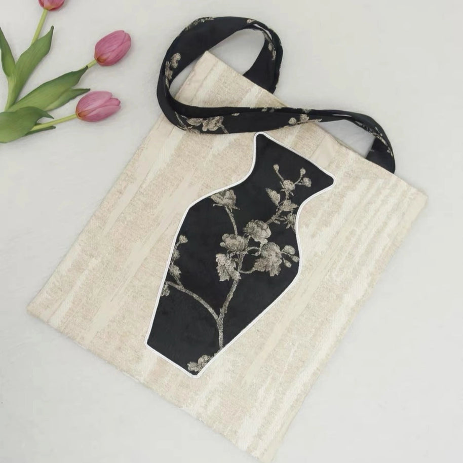 Close-up of the embroidered vase pocket on the black tote bag 