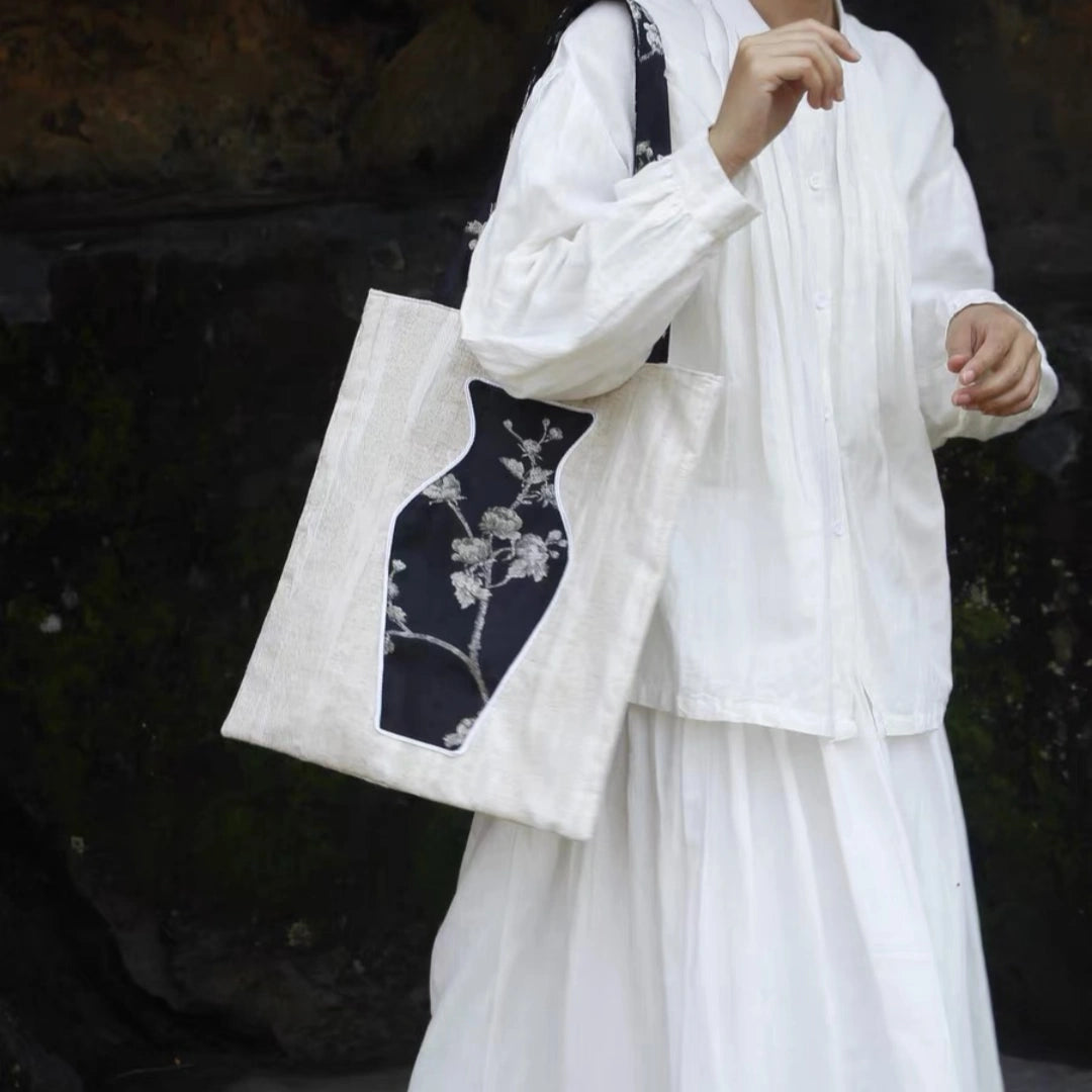 A stylish woman carrying The Black Blossom Tote, a sophisticated canvas bag featuring an interactive floral vase pocket.