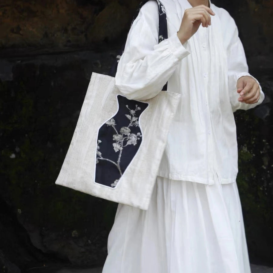 A stylish woman carrying The Black Blossom Tote, a sophisticated canvas bag featuring an interactive floral vase pocket.