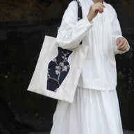 A stylish woman carrying The Black Blossom Tote, a sophisticated canvas bag featuring an interactive floral vase pocket.