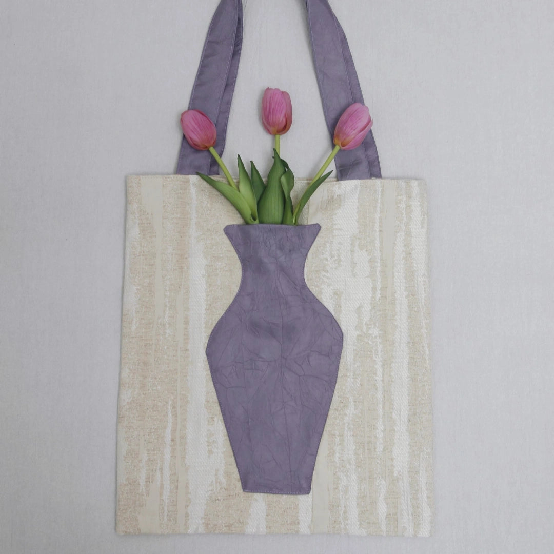 Close-up of The purple Blossom Tote, integrated pocket holding a fresh pink flower