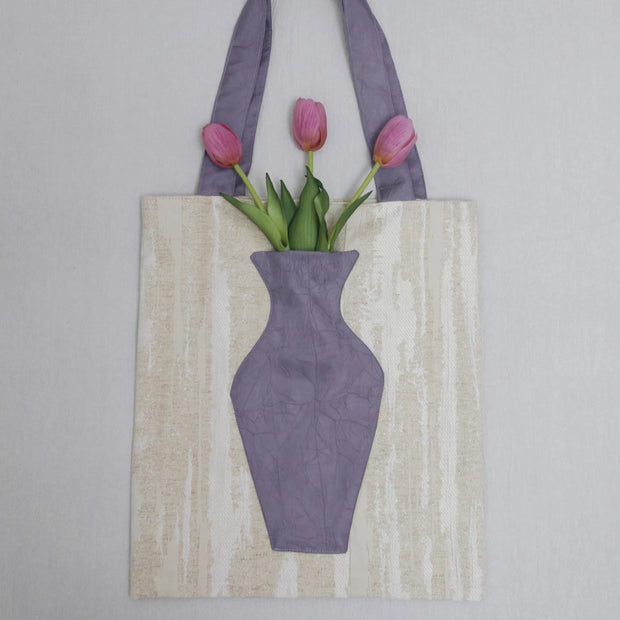 Close-up of The purple Blossom Tote, integrated pocket holding a fresh pink flower