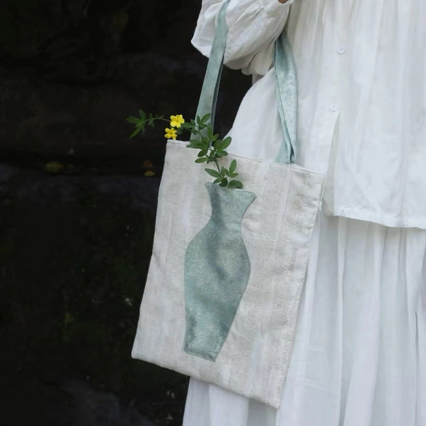 A woman in a white blazer carrying The Green Blossom Tote, an aesthetic canvas bag with an interactive vase pocket holding fresh flowers.