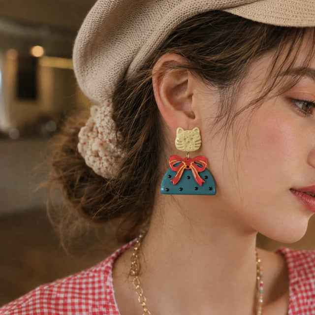 Close-up of Kitty Bow Statement Earrings with cream cat studs, red bows and teal polka-dot drops